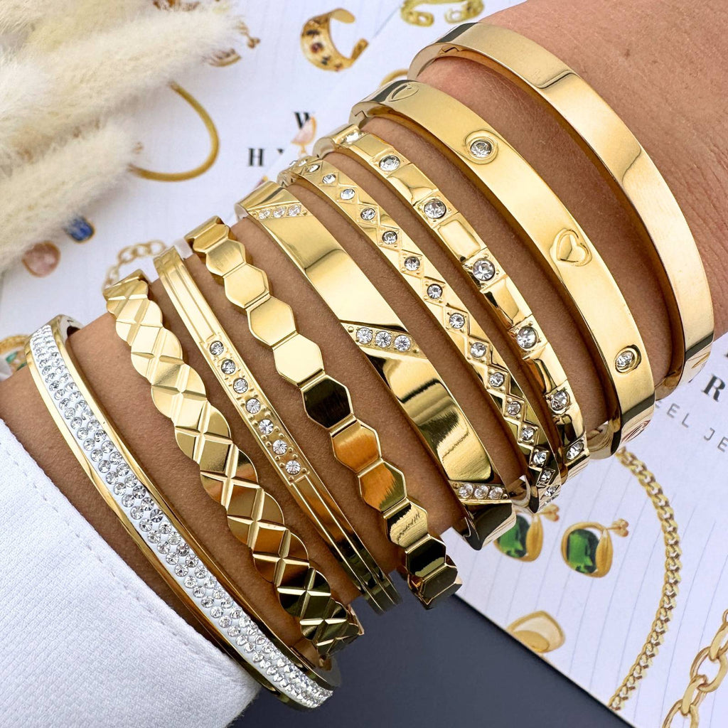 Mehrere goldfarbene Armreifen, teils mit Strass und geometrischem Relief