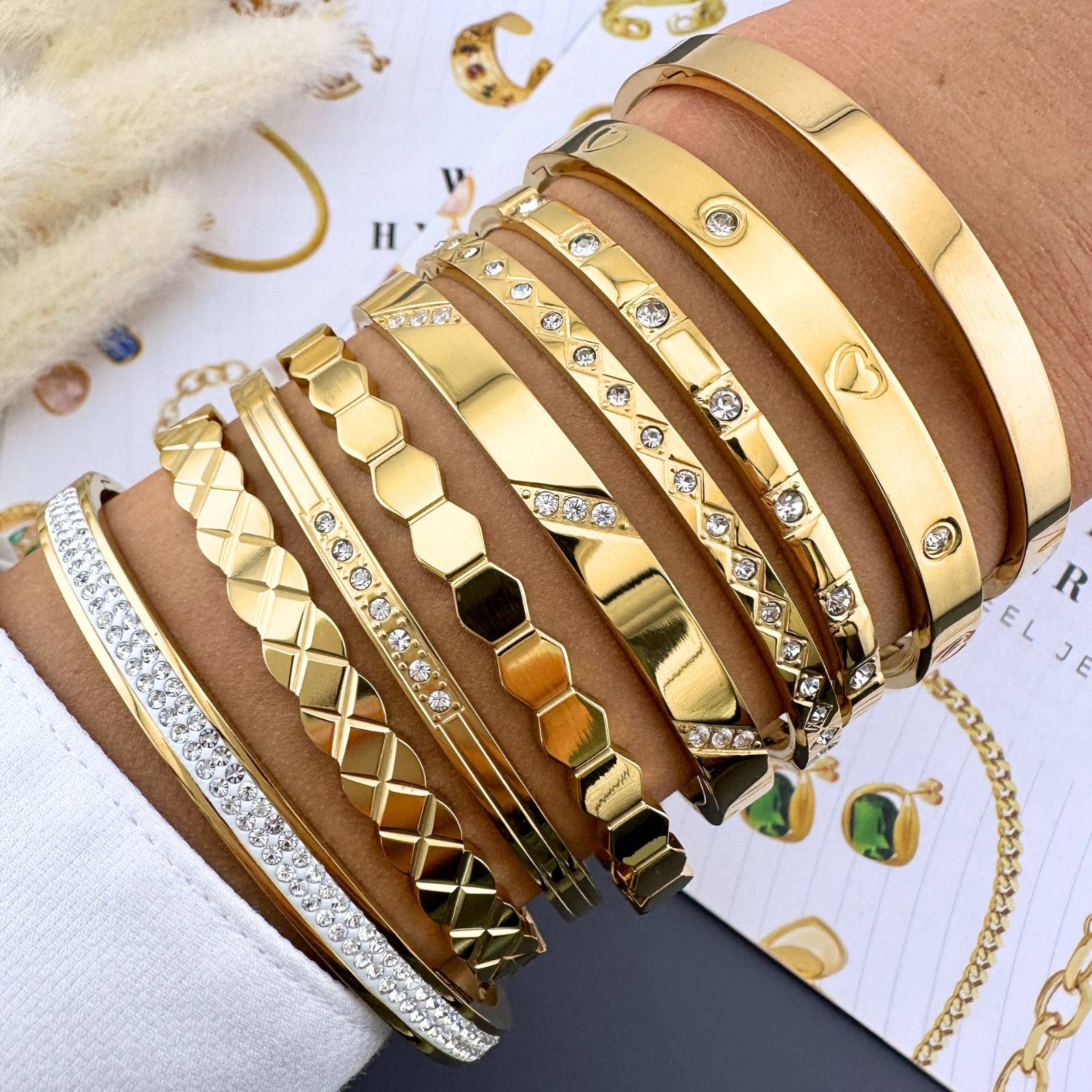 Mehrere goldfarbene Armreifen, teils mit Strass und geometrischem Relief