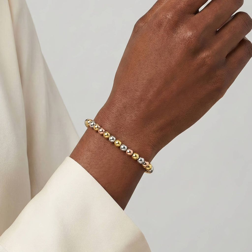 Dreireihiges Perlenarmband am Handgelenk mit Kugelperlen in Gold- und Silberfarben