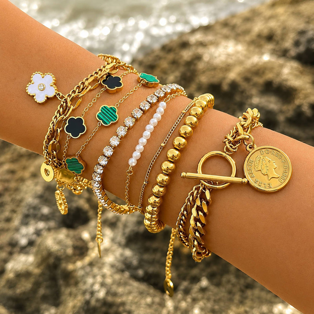 Goldfarbenes Armband am Handgelenk mit Münzanhänger, Steckverschluss und Schmuckdetails