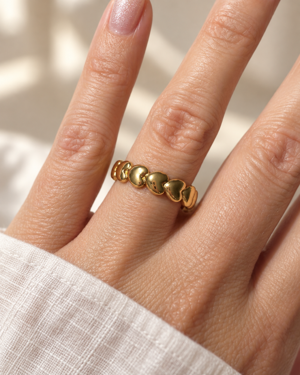 Frau trägt den goldfarbenen AMORA Ring mit Herzsegmenten am Finger